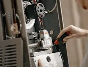Furnace repair technician inspecting internal components and wiring in Champaign, IL