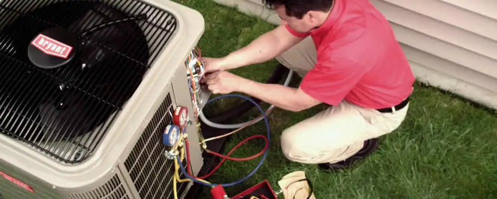HVAC technician servicing an outdoor air conditioner unit in Champaign, IL