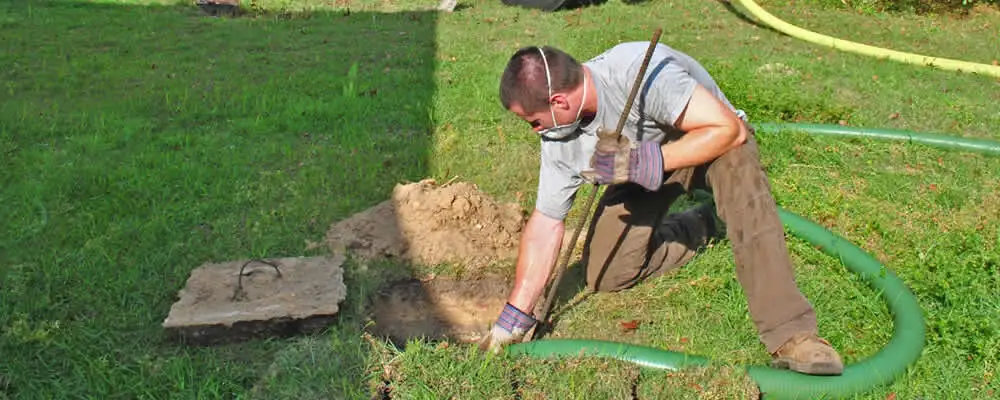 Septic pumping technician servicing a residential septic tank in Champaign, IL