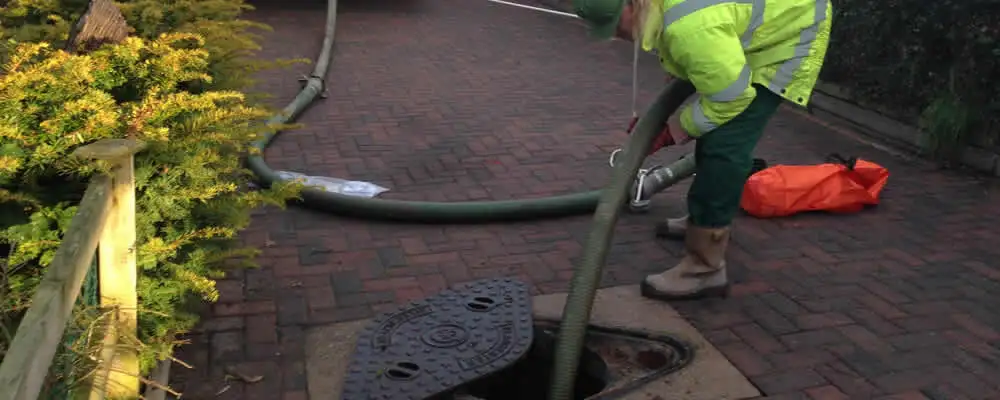 Septic tank cleaning technician servicing a septic tank with a vacuum hose in Champaign, IL