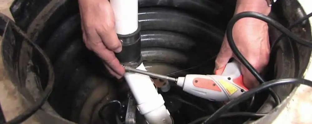 Sump pump installation technician connecting PVC discharge piping in Champaign, IL