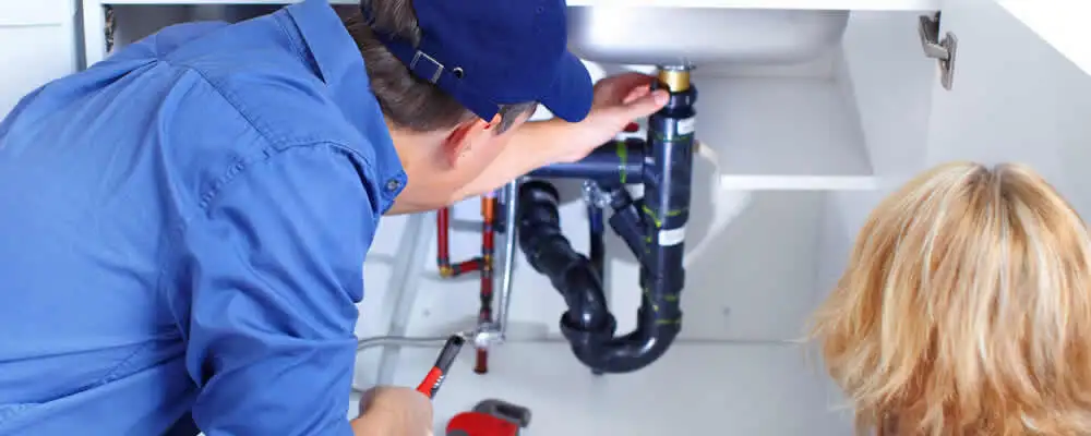 Plumber repairing under-sink drain pipes and fittings in Champaign, IL