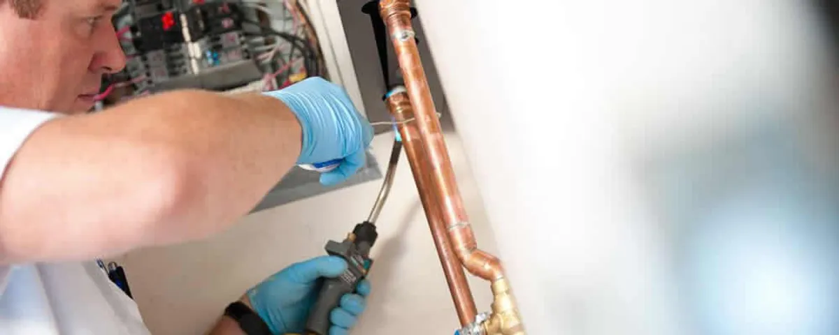 Water heater repair technician testing copper pipe connections and controls in Champaign, IL